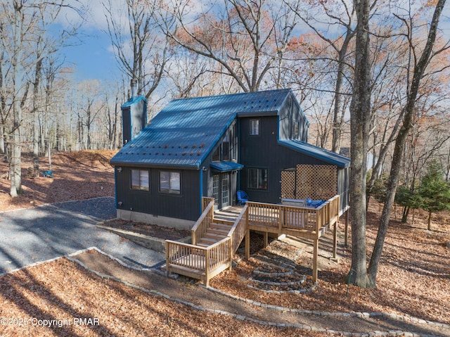 chalet / cabin featuring metal roof, a chimney, and gravel driveway