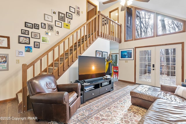 living area with baseboards, a towering ceiling, wood finished floors, stairs, and french doors