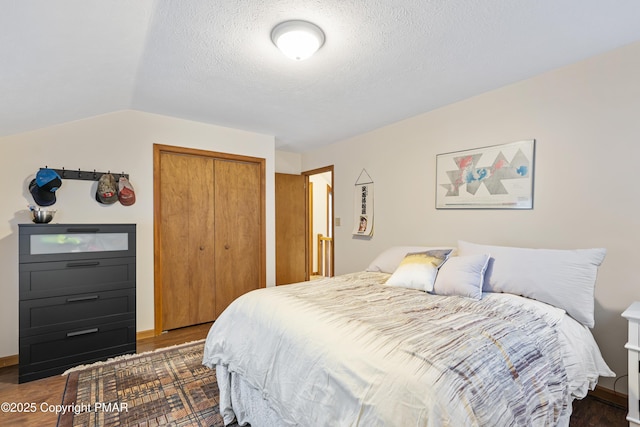 bedroom featuring lofted ceiling, a closet, a textured ceiling, and wood finished floors