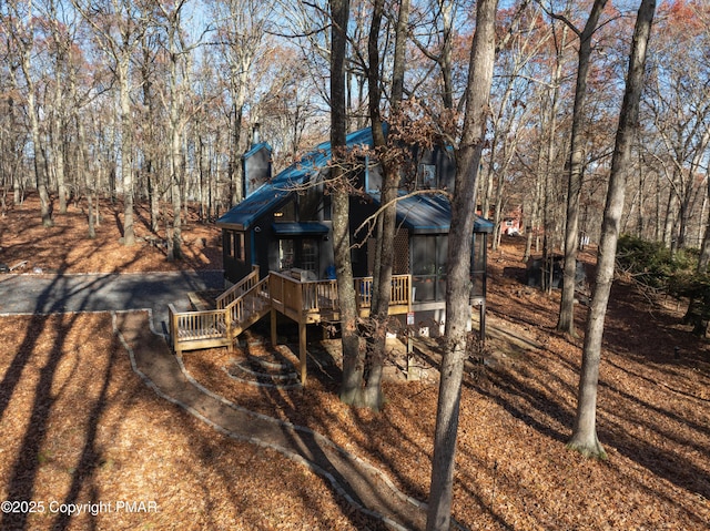 rear view of house with a deck, driveway, and a chimney