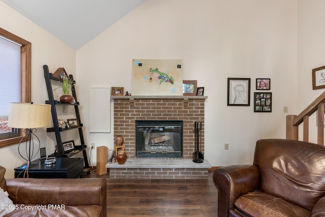 living room featuring a fireplace, vaulted ceiling, stairway, and wood finished floors