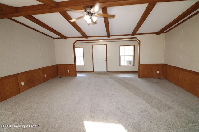 carpeted empty room featuring a wainscoted wall, plenty of natural light, and wooden walls