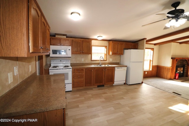 kitchen with white appliances, brown cabinetry, a sink, and wainscoting