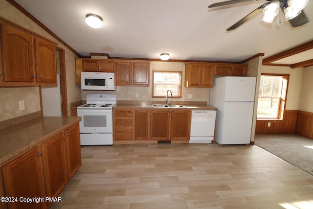 kitchen with a wainscoted wall, white appliances, brown cabinetry, and a sink