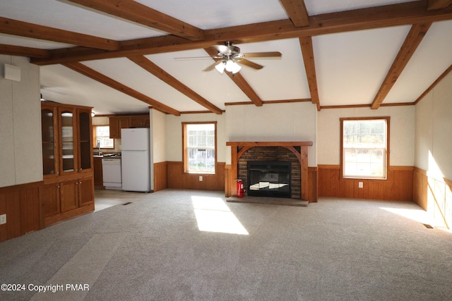 unfurnished living room featuring a healthy amount of sunlight, vaulted ceiling with beams, a fireplace, and wainscoting