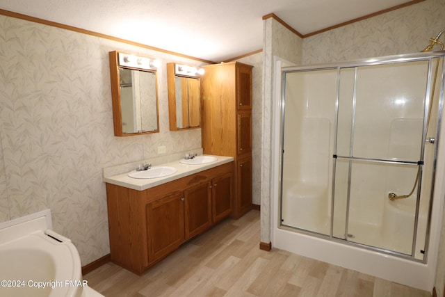 bathroom featuring wallpapered walls, crown molding, wood finished floors, and a stall shower