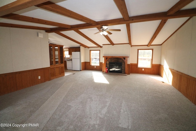 unfurnished living room with a glass covered fireplace, a wainscoted wall, vaulted ceiling with beams, and wood walls