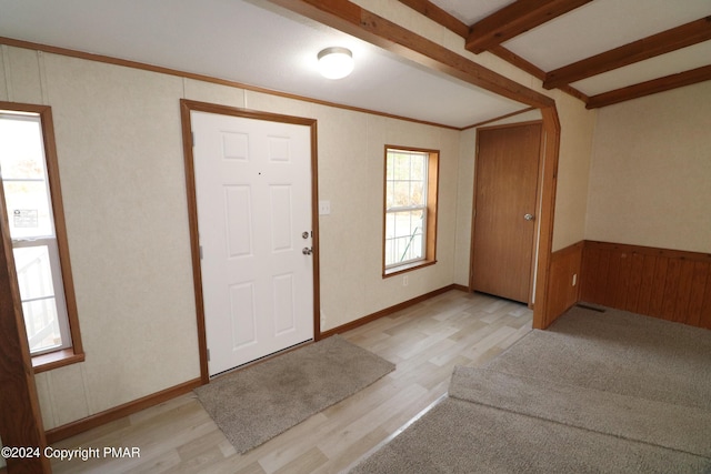 entrance foyer featuring lofted ceiling with beams, wainscoting, ornamental molding, and light wood-type flooring