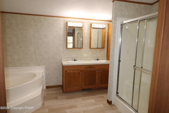 bathroom with a garden tub, wood finished floors, a sink, a stall shower, and wallpapered walls