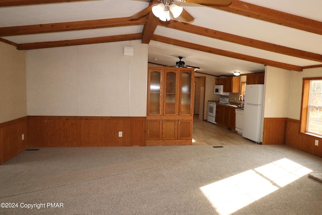 unfurnished living room featuring vaulted ceiling with beams, wainscoting, ceiling fan, wooden walls, and light carpet