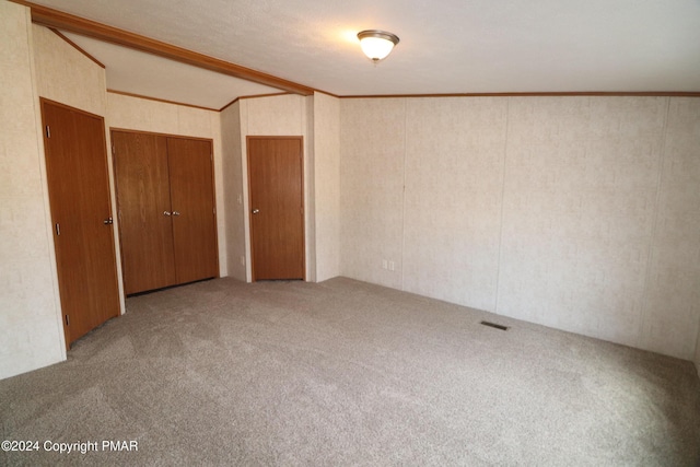 unfurnished bedroom featuring ornamental molding, carpet, visible vents, and two closets