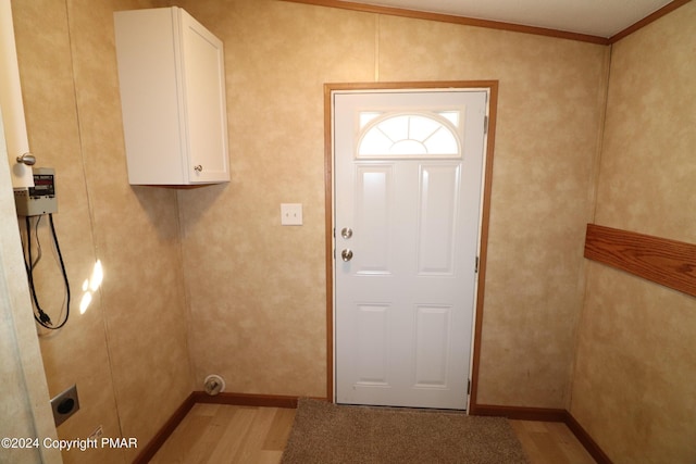 laundry room with ornamental molding, light wood-style flooring, cabinet space, and electric dryer hookup