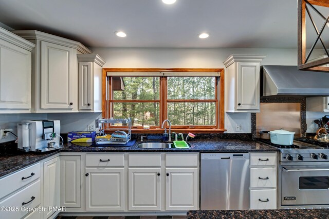 kitchen featuring appliances with stainless steel finishes, sink, wall chimney range hood, and white cabinets