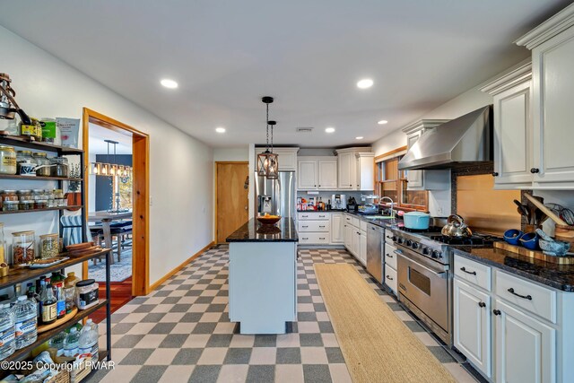 kitchen with pendant lighting, sink, appliances with stainless steel finishes, a center island, and wall chimney exhaust hood