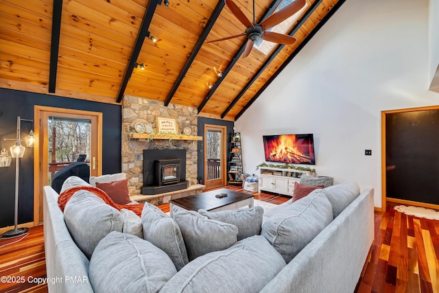 living room with beamed ceiling, a wood stove, hardwood / wood-style flooring, ceiling fan, and wood ceiling