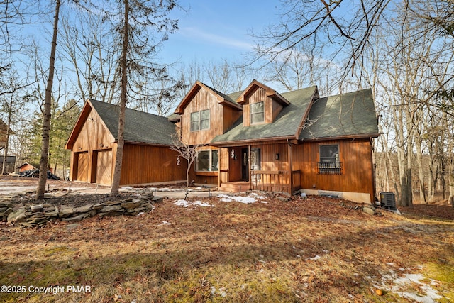 chalet / cabin featuring central air condition unit, roof with shingles, and a porch