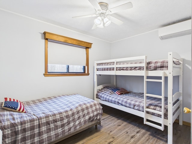 bedroom featuring a ceiling fan, an AC wall unit, and wood finished floors