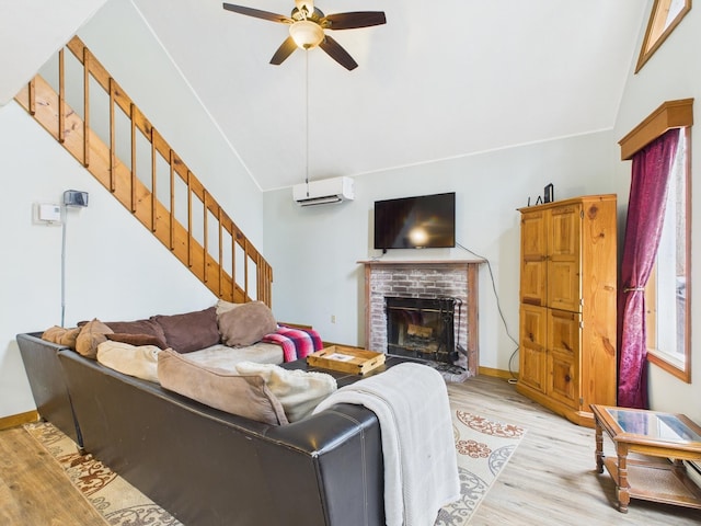 living area with ceiling fan, light wood-style floors, stairway, a wall mounted AC, and a brick fireplace