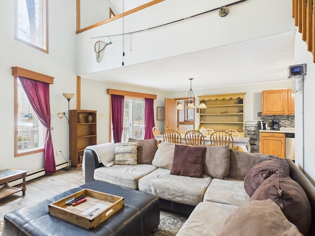 living area with light wood-type flooring, a baseboard radiator, and a chandelier