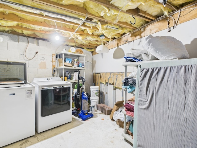 clothes washing area featuring washer and dryer, laundry area, and concrete block wall