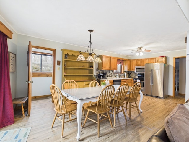 dining space featuring baseboards, light wood-style flooring, and a ceiling fan