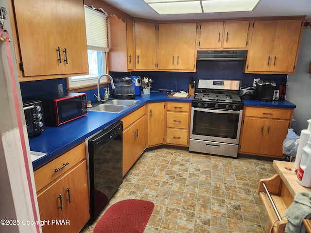 kitchen featuring stainless steel gas range, a sink, stone finish floor, under cabinet range hood, and dishwasher