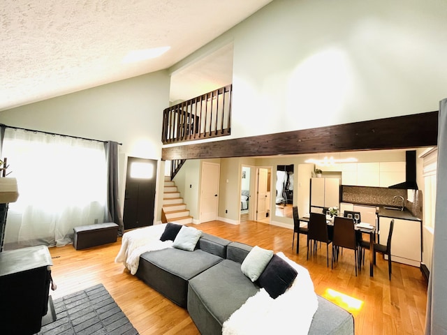 8540 Hillcrest Dr, Tobyhanna, PA 18466 - living room featuring high vaulted ceiling, stairs, light wood-style floors, and a textured ceiling