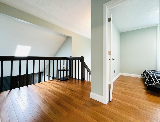 8540 Hillcrest Dr, Tobyhanna, PA 18466 - corridor featuring wood finished floors, an upstairs landing, vaulted ceiling, and a textured ceiling