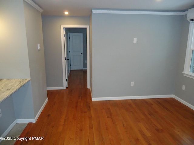 unfurnished room with wood-type flooring, a wall mounted AC, and crown molding