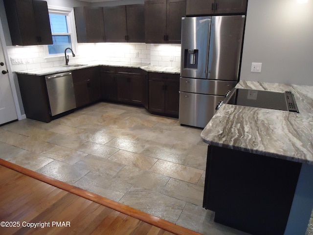 kitchen featuring appliances with stainless steel finishes, sink, and light stone counters