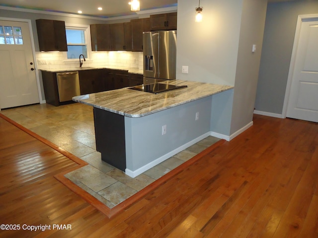 kitchen with dark brown cabinetry, stainless steel appliances, light hardwood / wood-style flooring, and backsplash