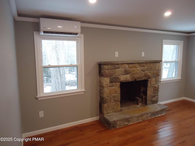 living room with crown molding, a wall mounted air conditioner, a stone fireplace, and hardwood / wood-style flooring