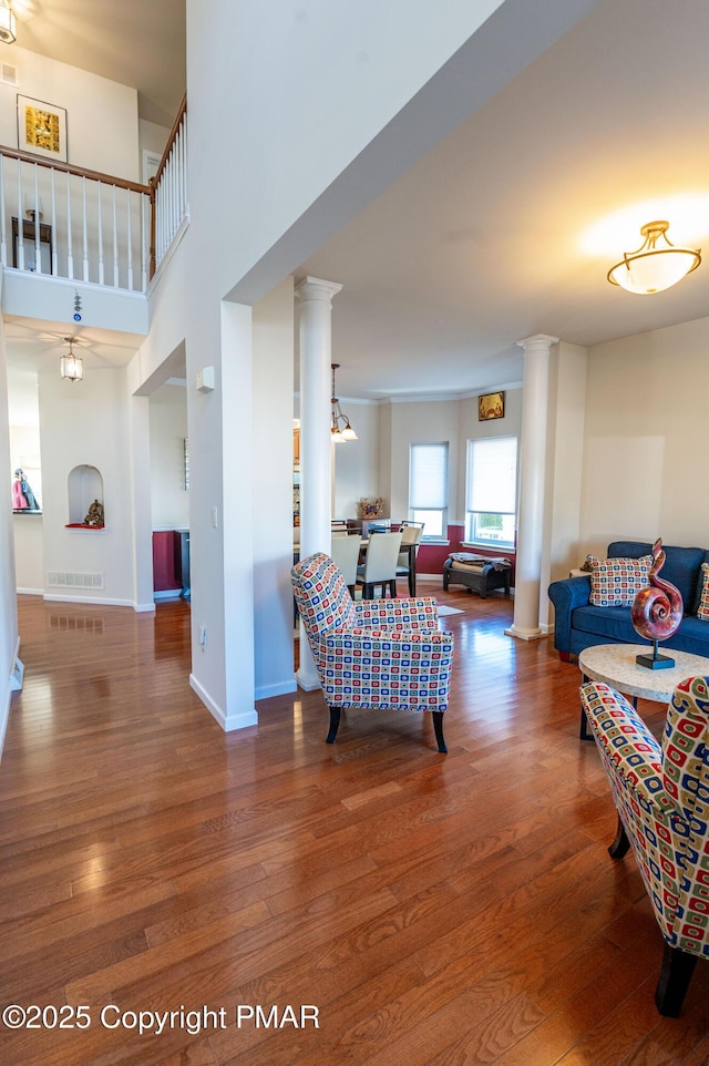 living room with a high ceiling, decorative columns, and hardwood / wood-style floors