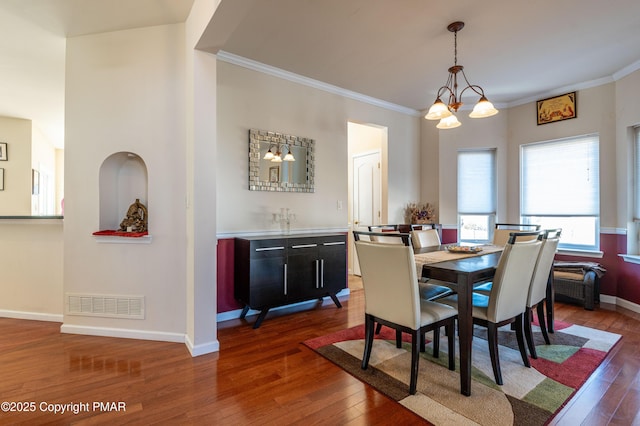 dining room featuring crown molding, dark hardwood / wood-style floors, and an inviting chandelier