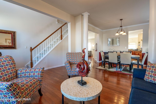 living room with crown molding, dark wood-type flooring, a notable chandelier, and ornate columns