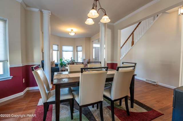 dining area with ornate columns, hardwood / wood-style floors, and crown molding