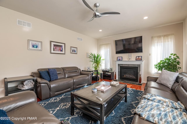 living room featuring a tile fireplace, ceiling fan, and wood-type flooring