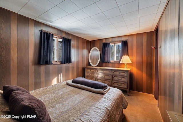 bedroom with light carpet and wooden walls