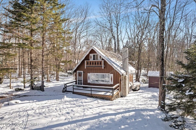 chalet / cabin featuring a deck, a chimney, and a detached garage