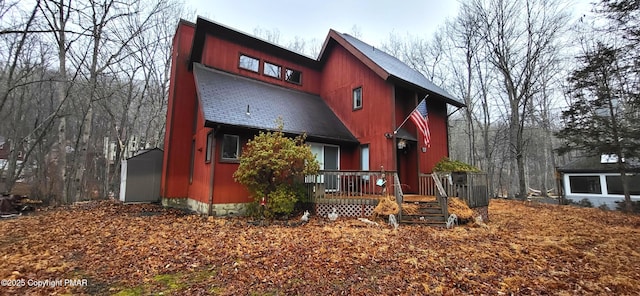 view of front of house featuring a deck and roof with shingles