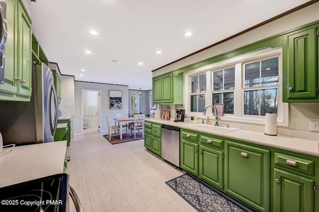 kitchen featuring green cabinets, stainless steel dishwasher, a sink, and crown molding