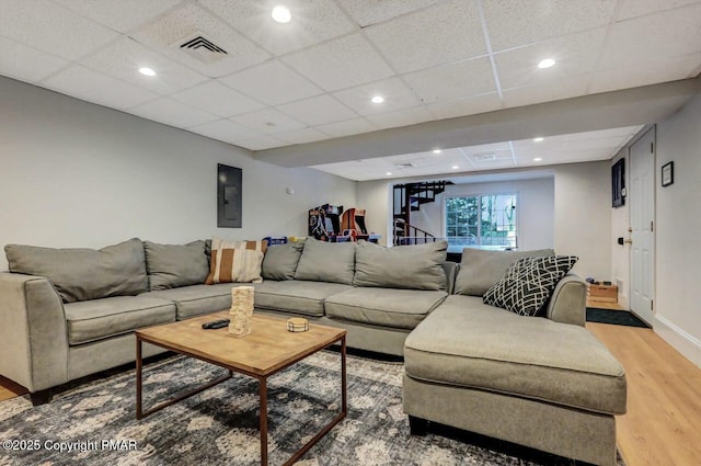 living room featuring a paneled ceiling, recessed lighting, stairway, light wood-style floors, and baseboards