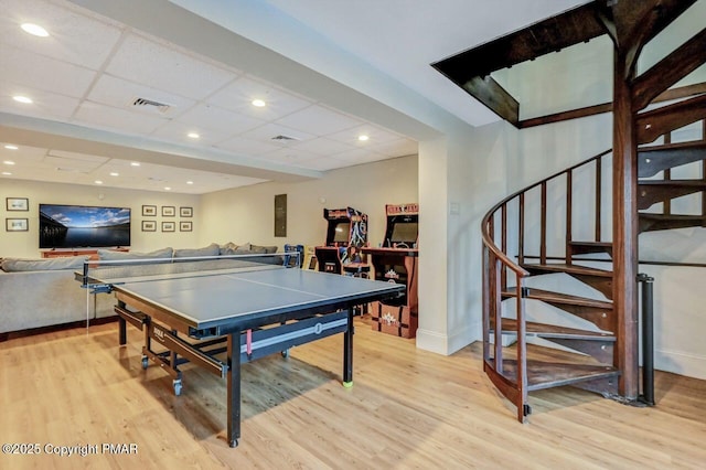 recreation room featuring light wood finished floors, baseboards, visible vents, and a drop ceiling