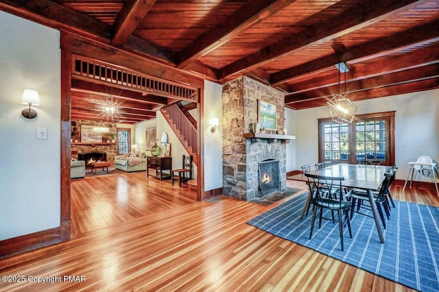 dining area featuring wooden ceiling, a fireplace, wood finished floors, beamed ceiling, and an inviting chandelier