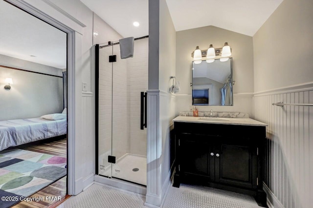 full bath featuring lofted ceiling, a stall shower, vanity, and a wainscoted wall