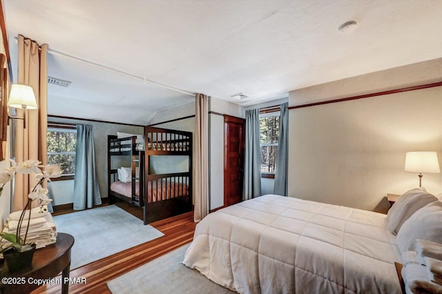 bedroom with multiple windows, visible vents, and wood finished floors