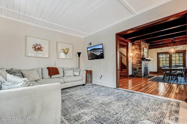 living room featuring a fireplace, stairway, wood finished floors, beamed ceiling, and baseboards