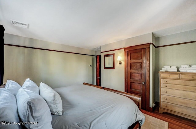 bedroom featuring wood finished floors and visible vents