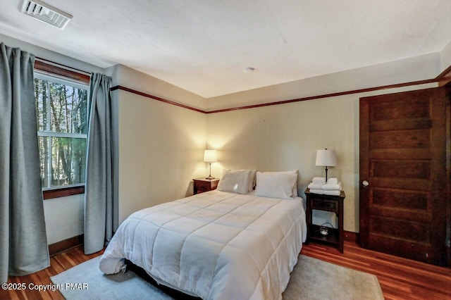 bedroom featuring visible vents, baseboards, and wood finished floors