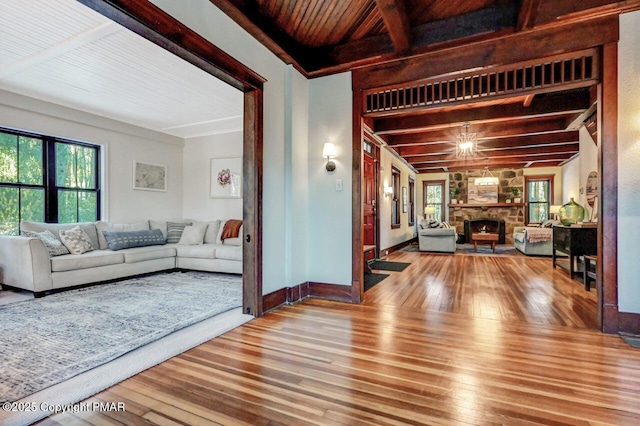 living room with baseboards, hardwood / wood-style flooring, a fireplace, a chandelier, and beam ceiling